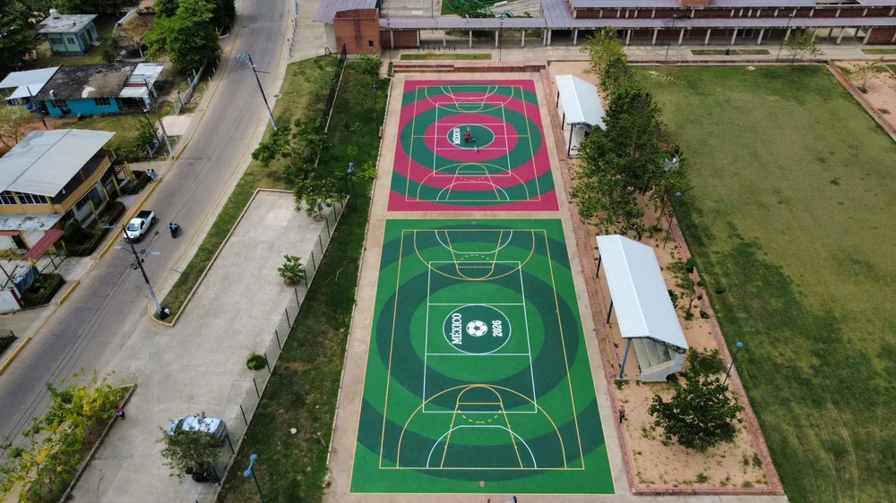 Vista aérea de dos canchas deportivas escolares con trazos de basquetbol pintadas en vino y verde en Cosoleacaque, Veracruz
