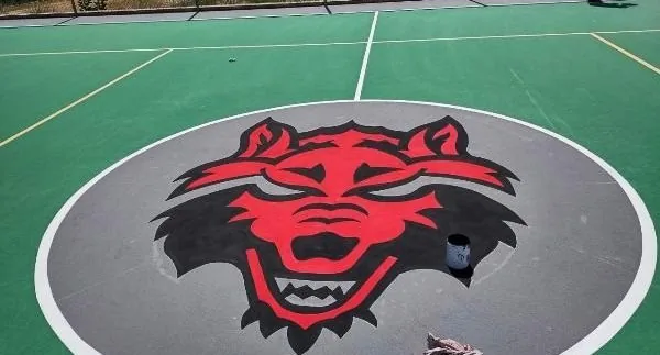 Escudo de Arkansas State University pintado en el centro de la cancha del Campus Querétaro por PLAYKO