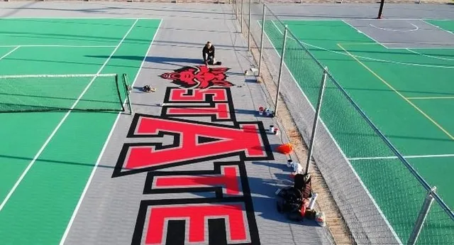 Rotulado institucional de Arkansas State University en la cancha, pintado por PLAYKO